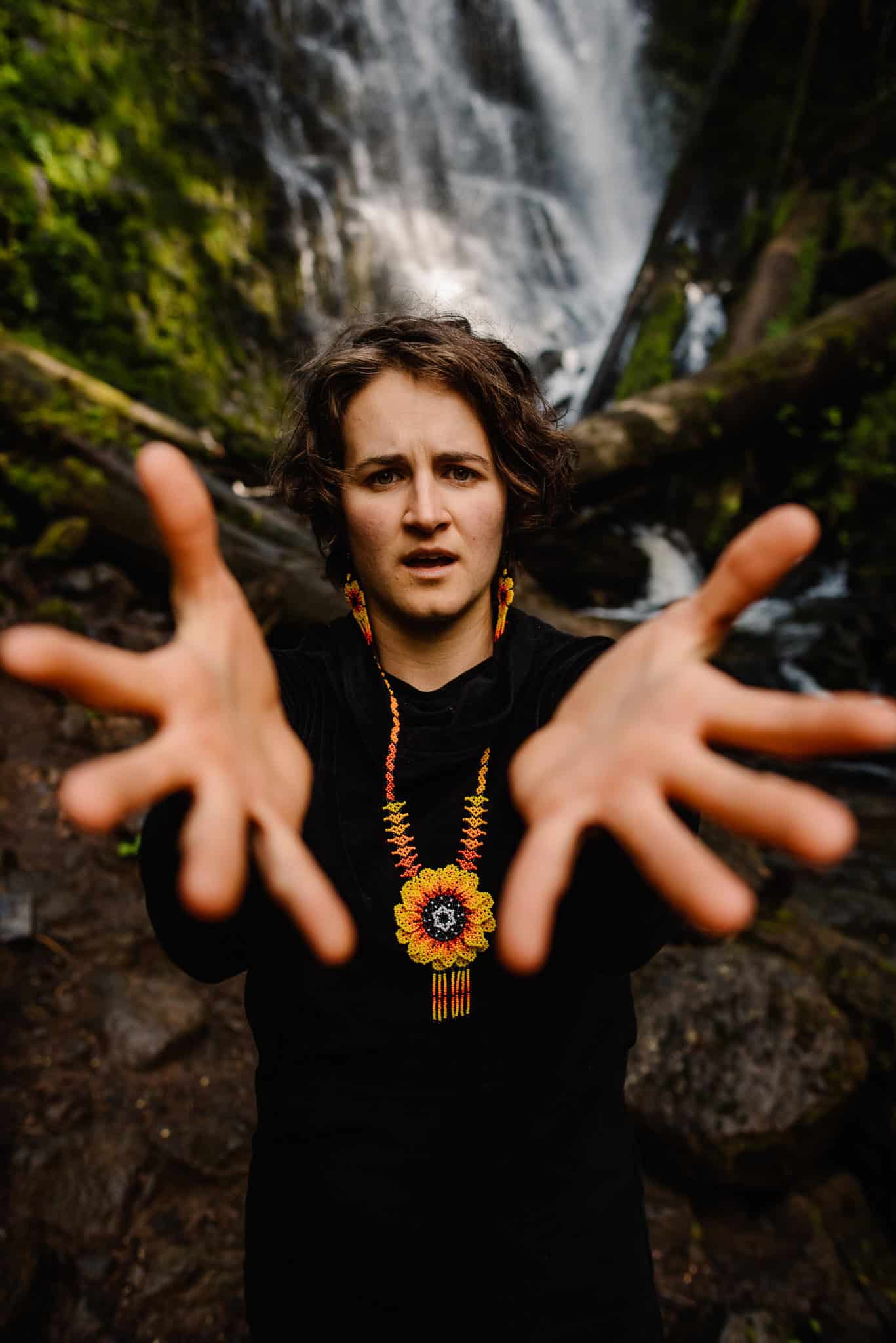 woman holding out hands near a waterfall at womens retreat in Oregon