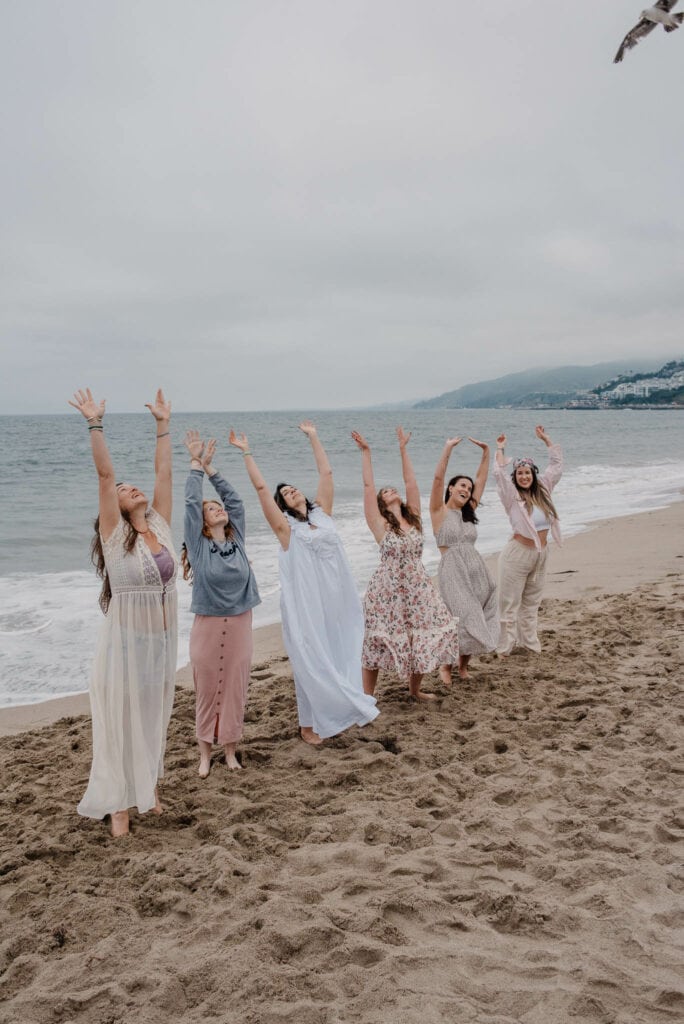 women gathering at a womens retreat on the coast of Oregon with arms raised up in celebration