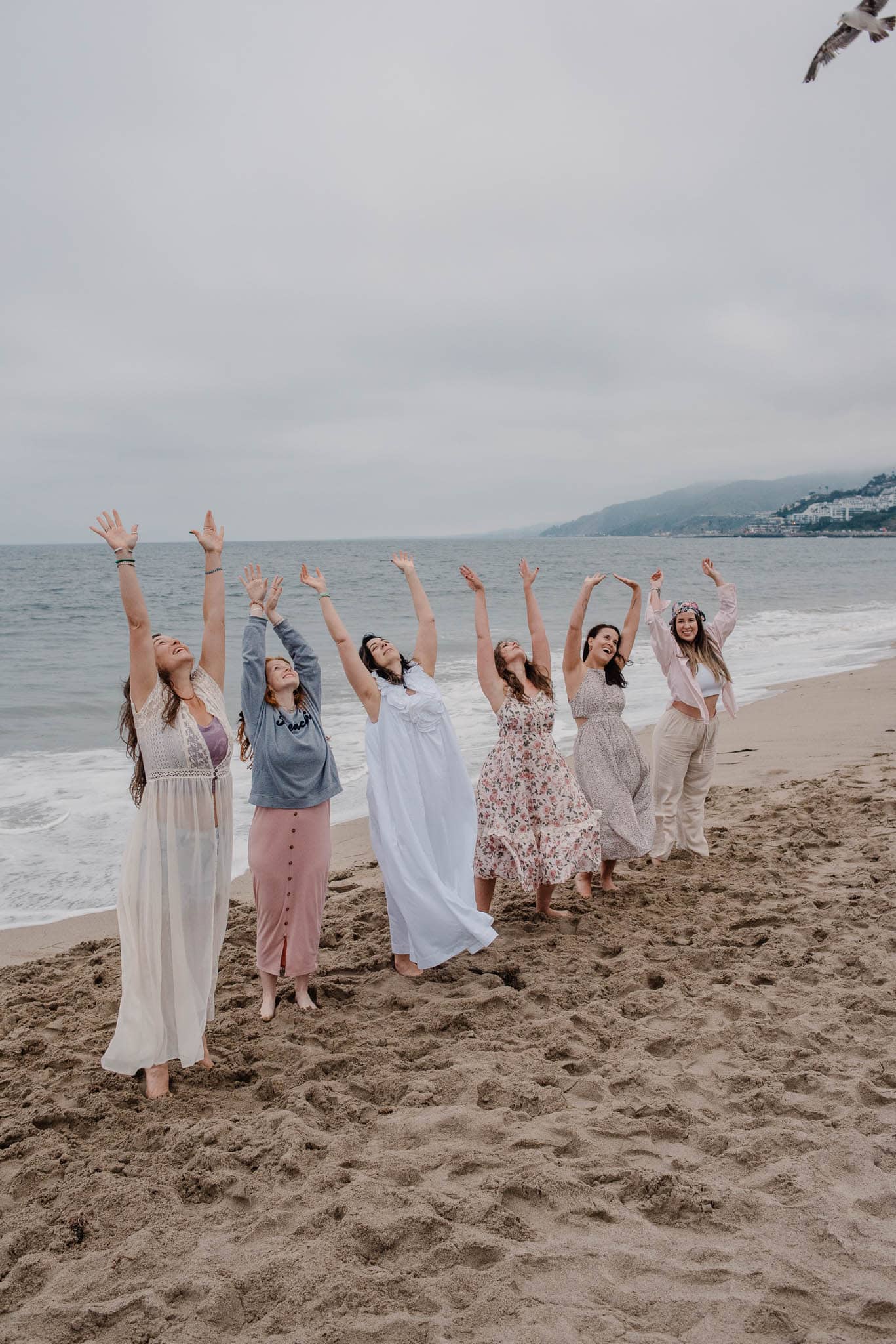 women gathering at a womens retreat on the coast of Oregon with arms raised up in celebration