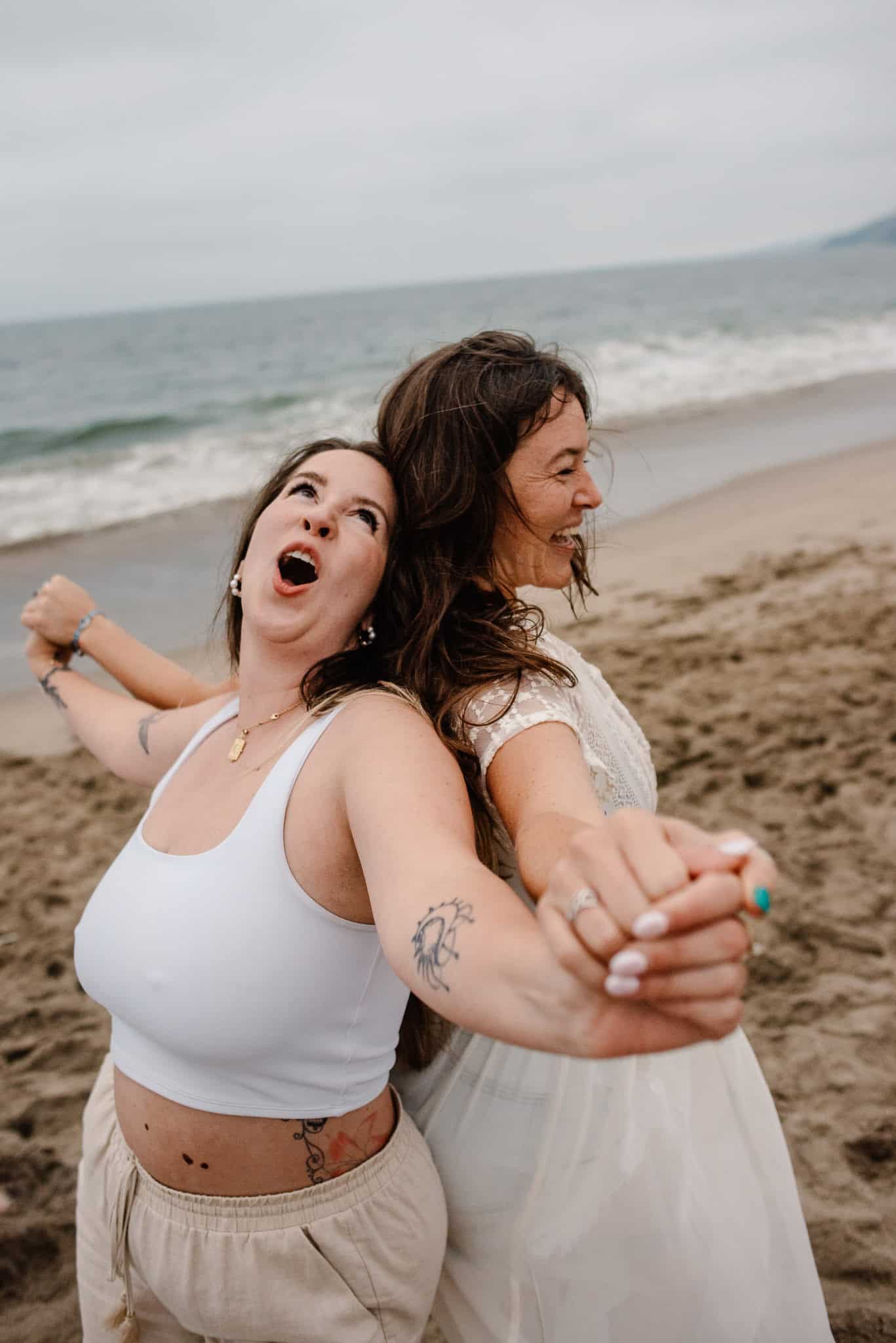 women back to back laughing near the oceanat a womens retreat in oregon