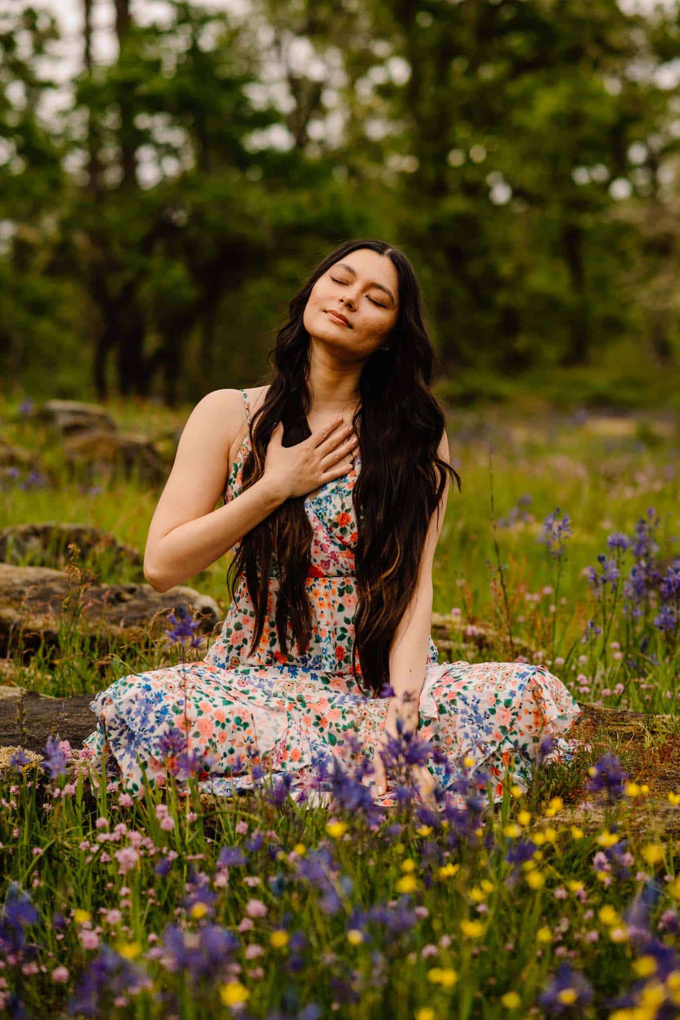 female meditating with her hand on her heart with wild flowers framing her for a women's retreat near portland oregon