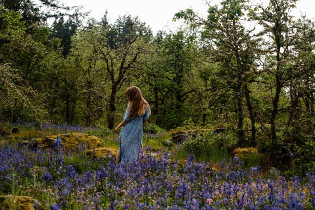 woman at a self love retreat with flower therapy gently walking in wild flowers