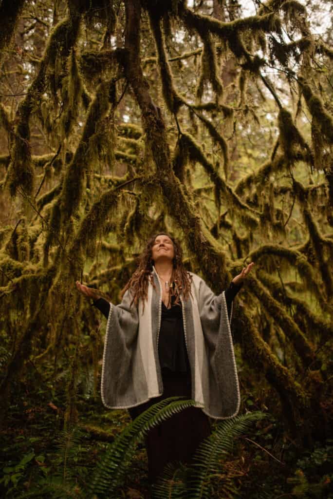 female holding hands out near a tree with hands raised up during a boudoir photography self love photography session outside of Portland, Oregon