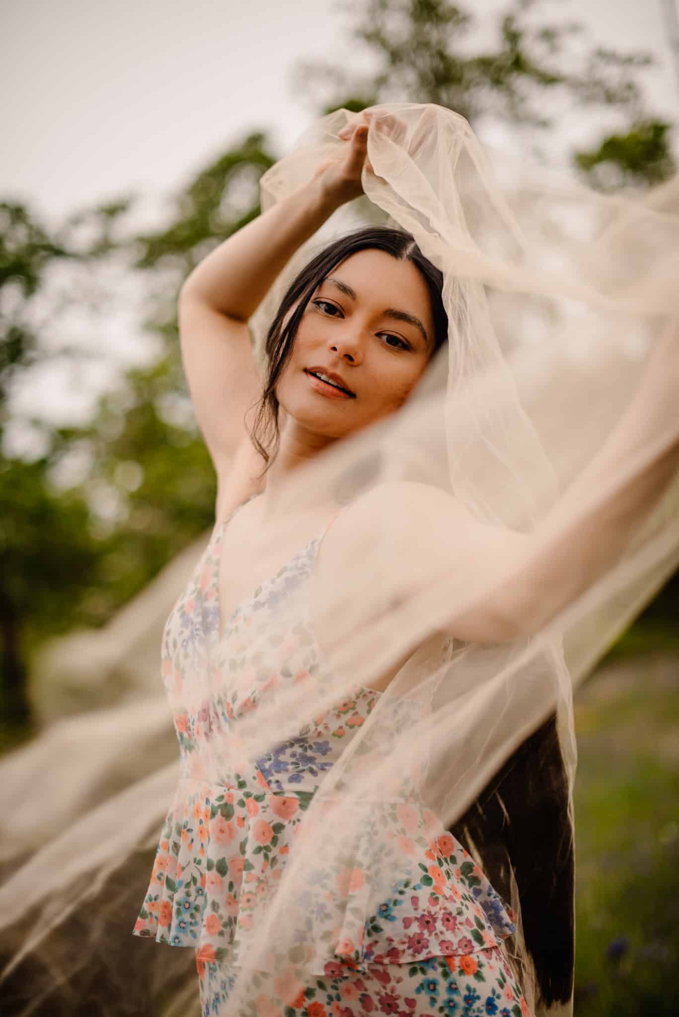 female holding up tulle and dancing around it during a boudoir photography self love photography session outside of Portland, Oregon