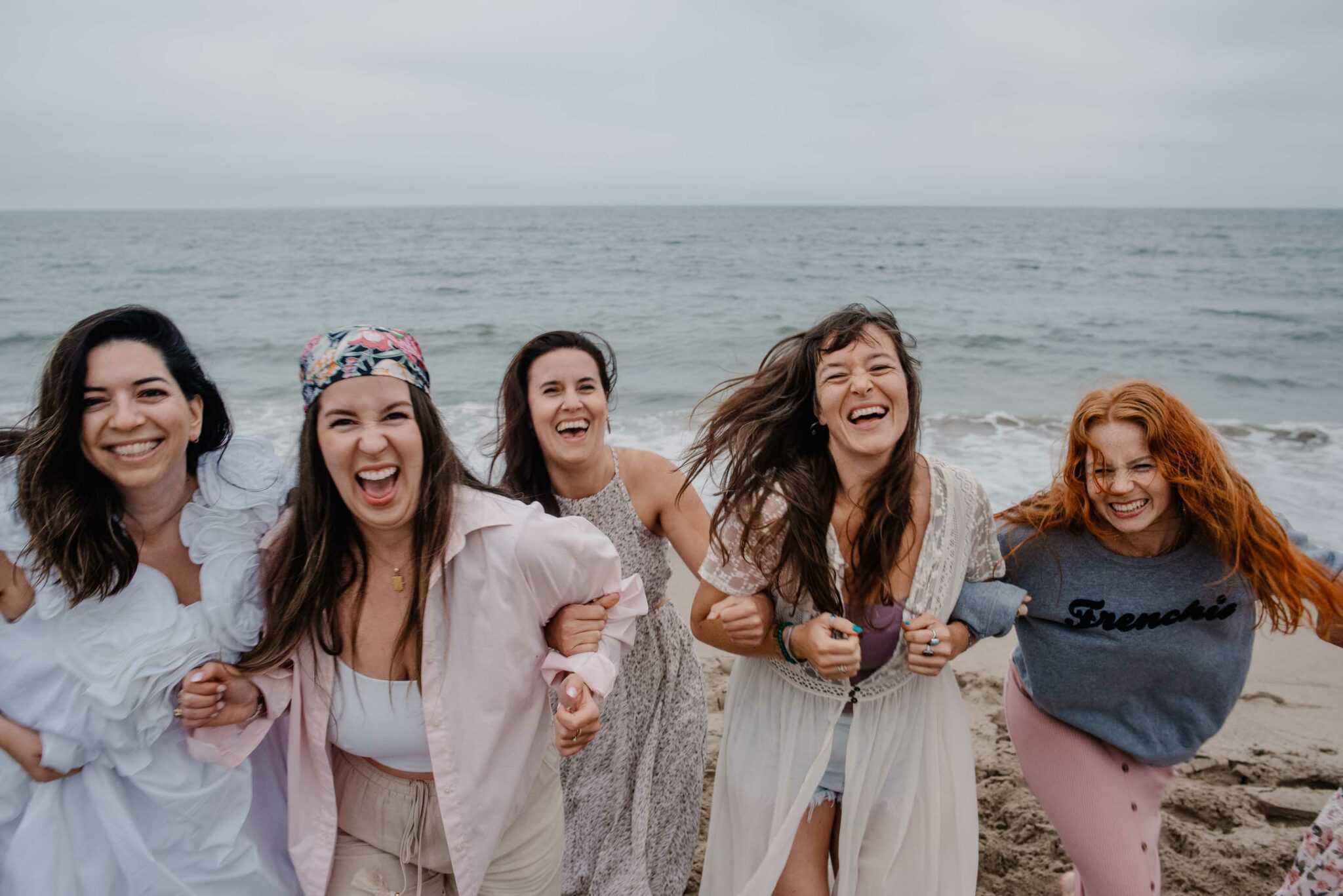 women linking arms at community boudior photography gathering on the Oregon coast