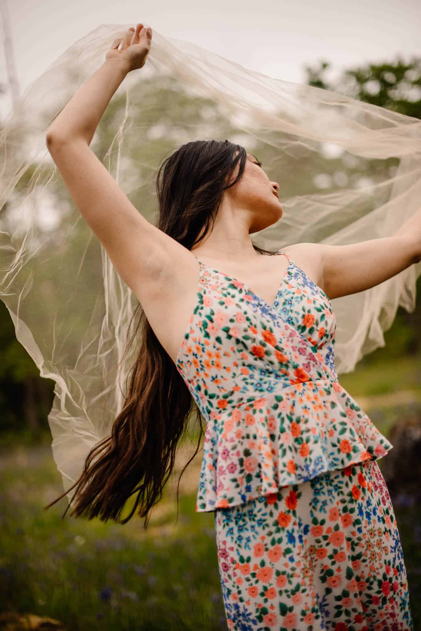 woman holding tule around her in a flower dress