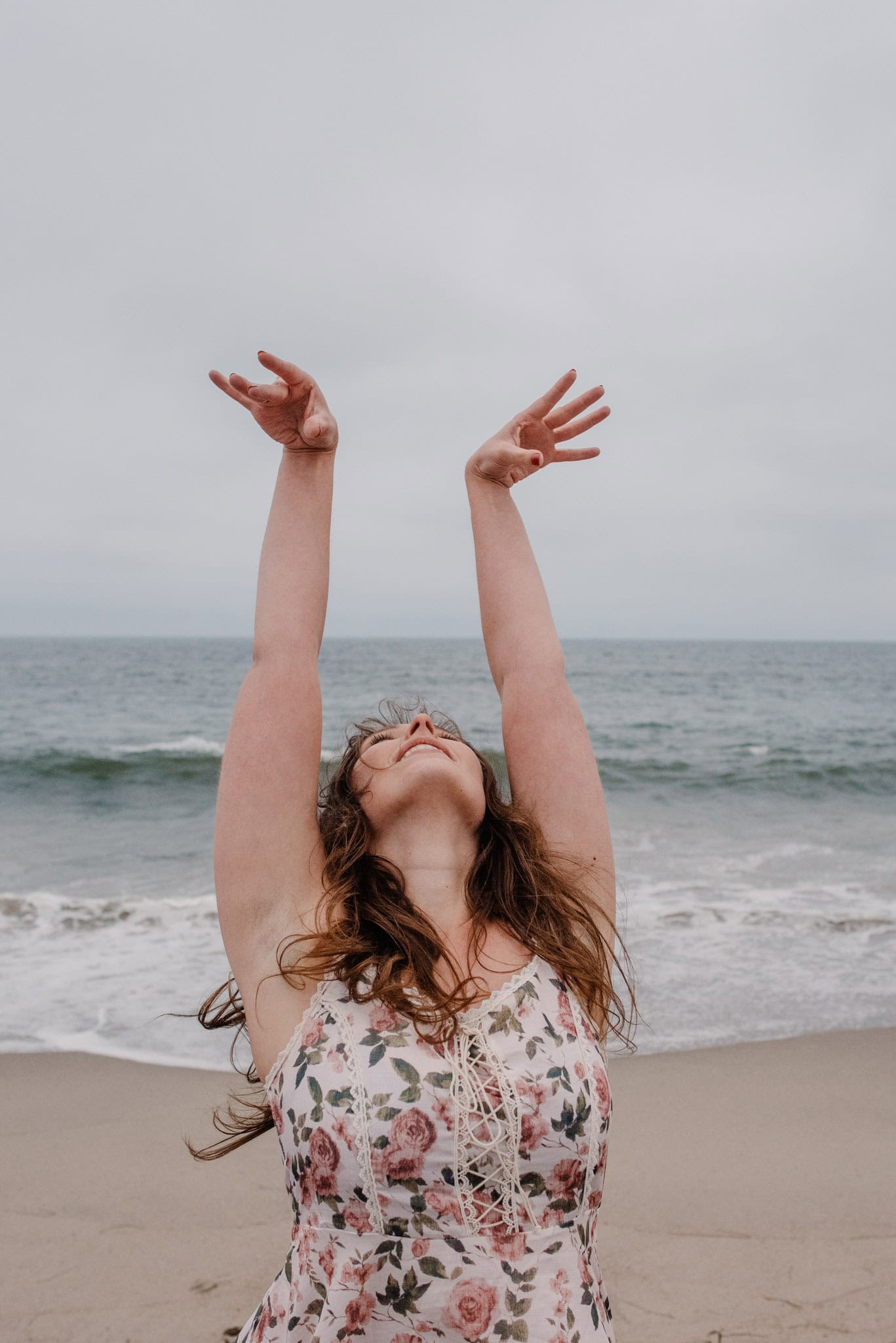 woman on the oregon coast with arms up and head back in a dress during an alteratnive boudoir photography pricing package