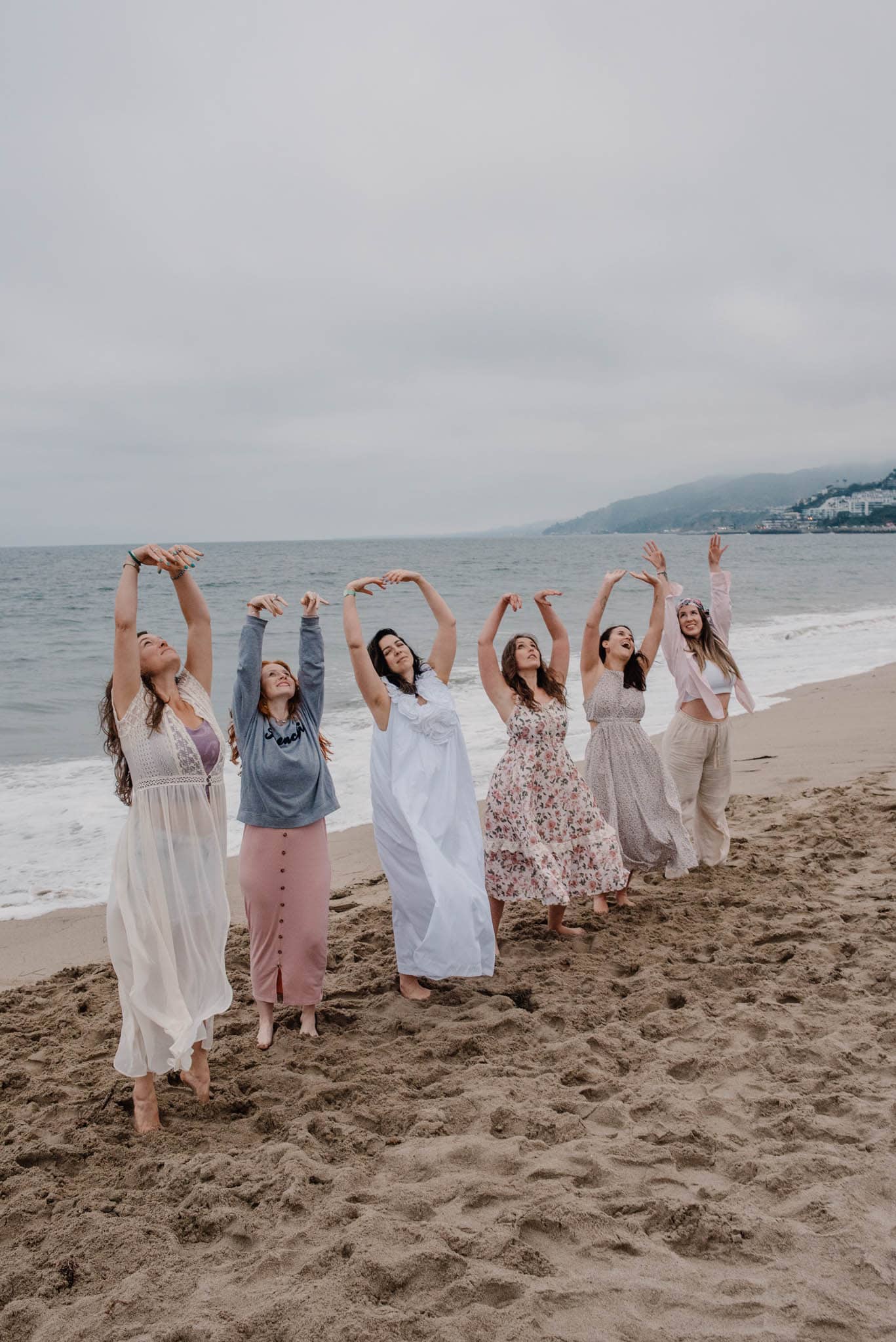 women raising arms up at community boudior photography gathering on the Oregon coast