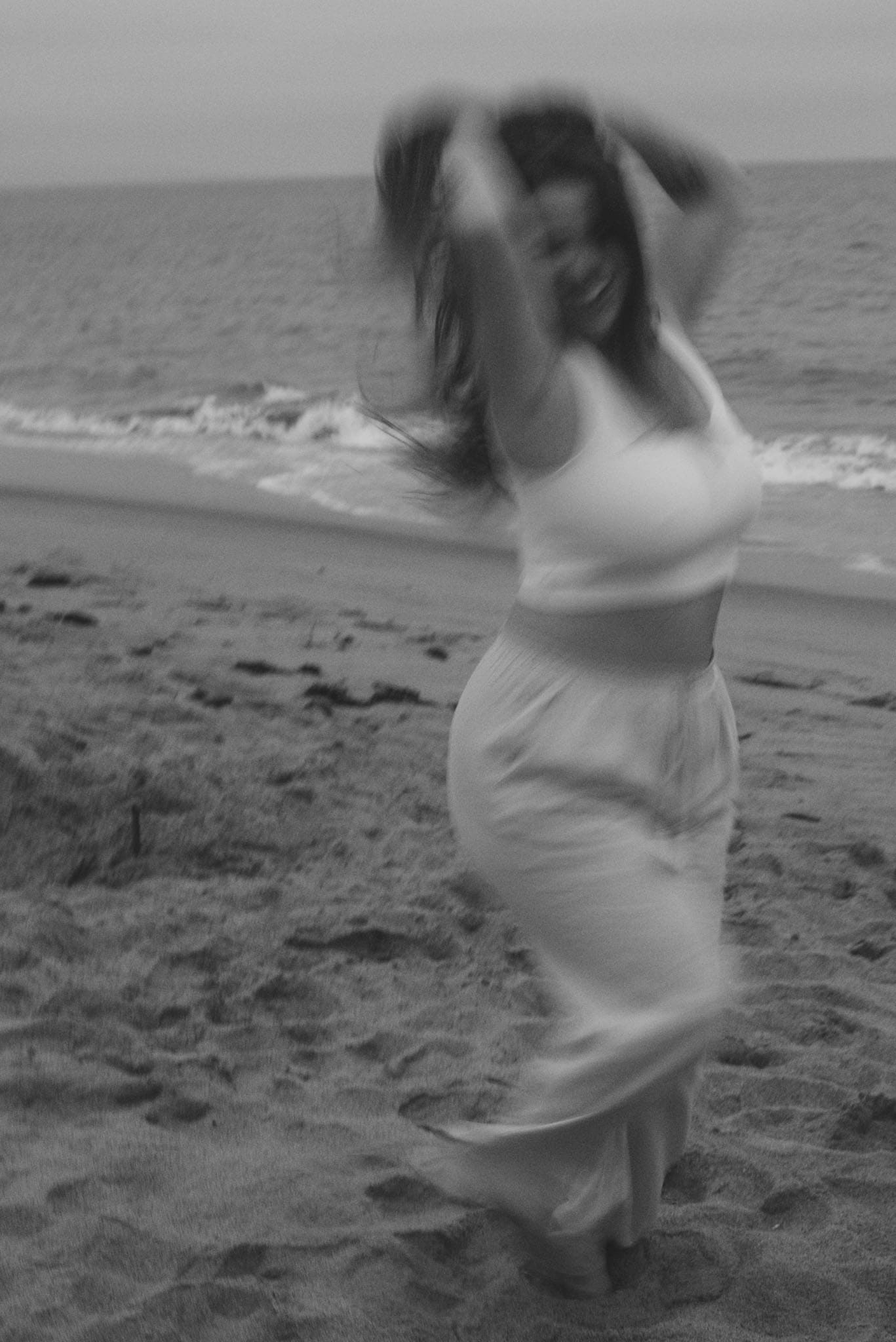 woman holding up hair on the beach black and white photo