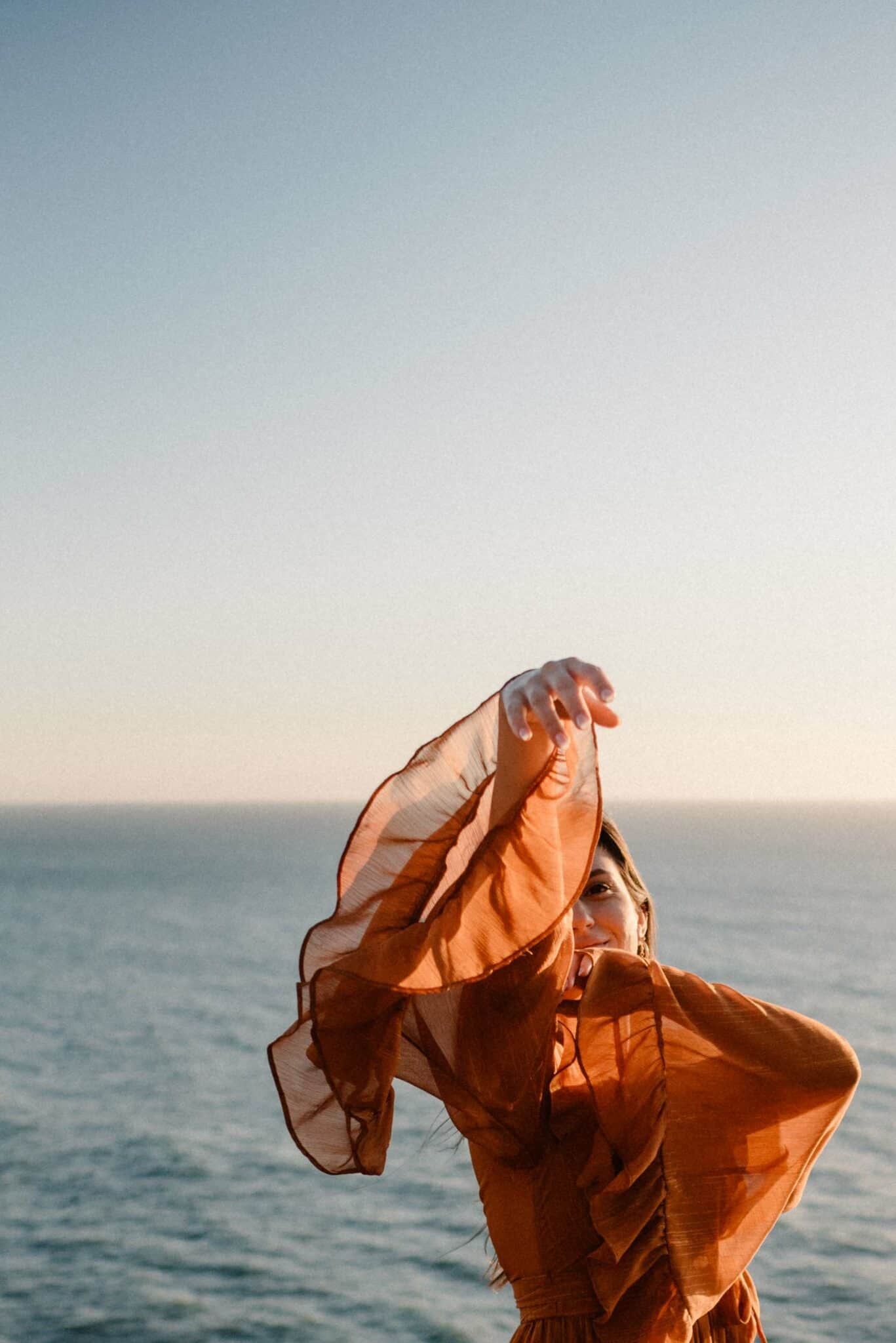 woman on the coast as siren archetype with arms up