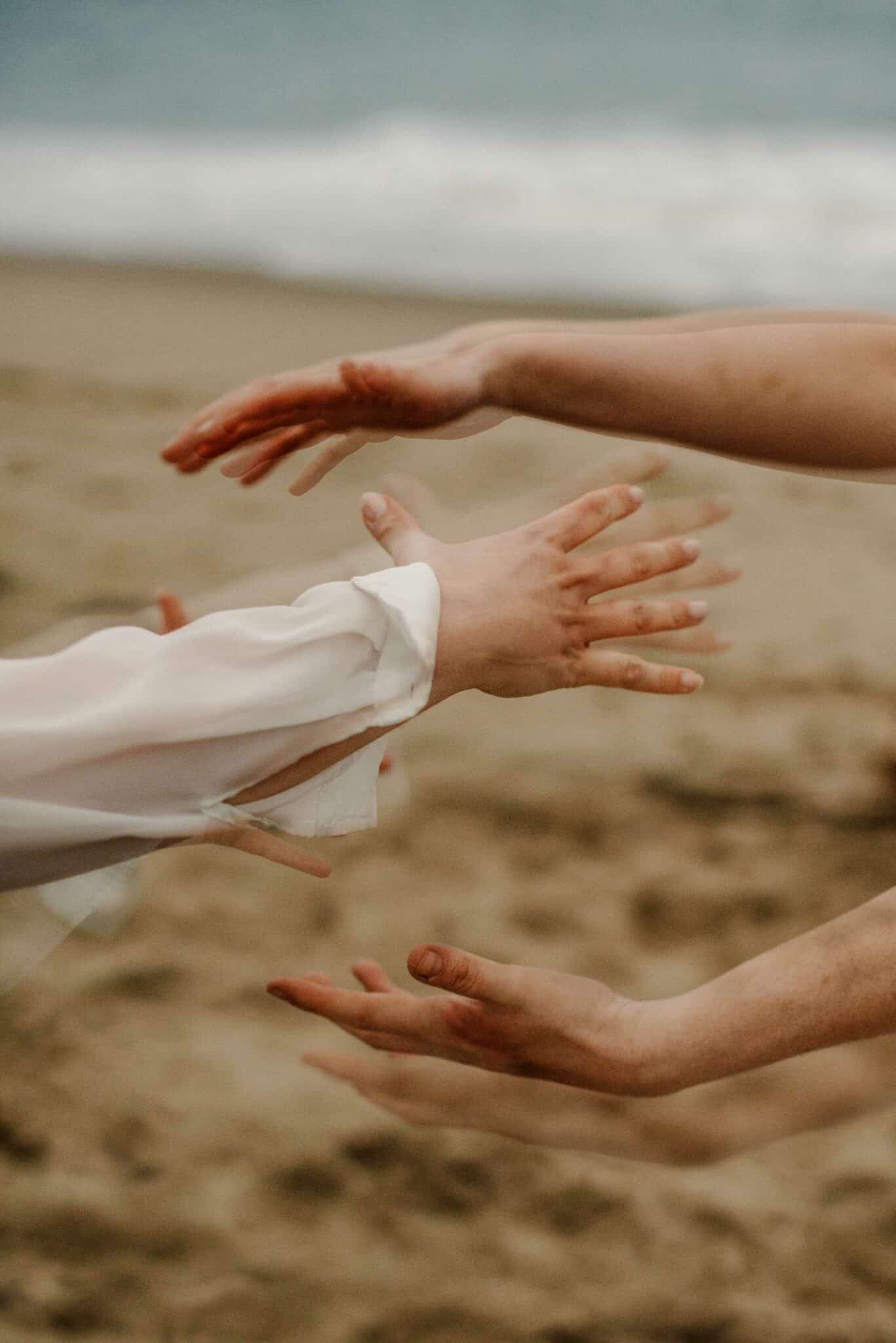 women holding hands in a fun shape near a coast practicing being the siren archetype