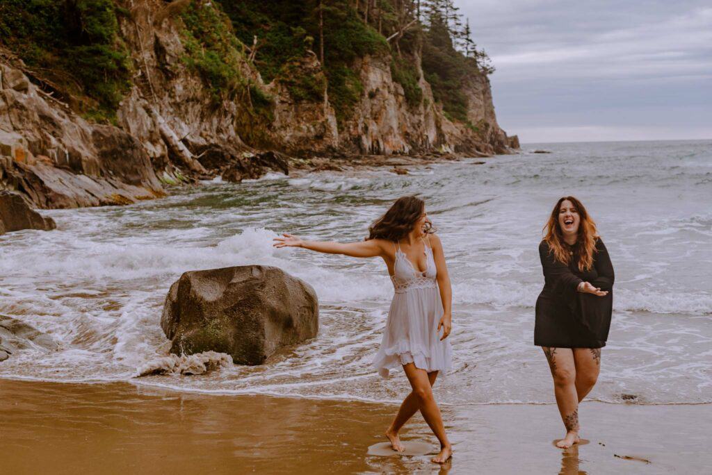 women gathered embodying the siren archetype at a womens retreat on the oregon coast splashing in the water playfully