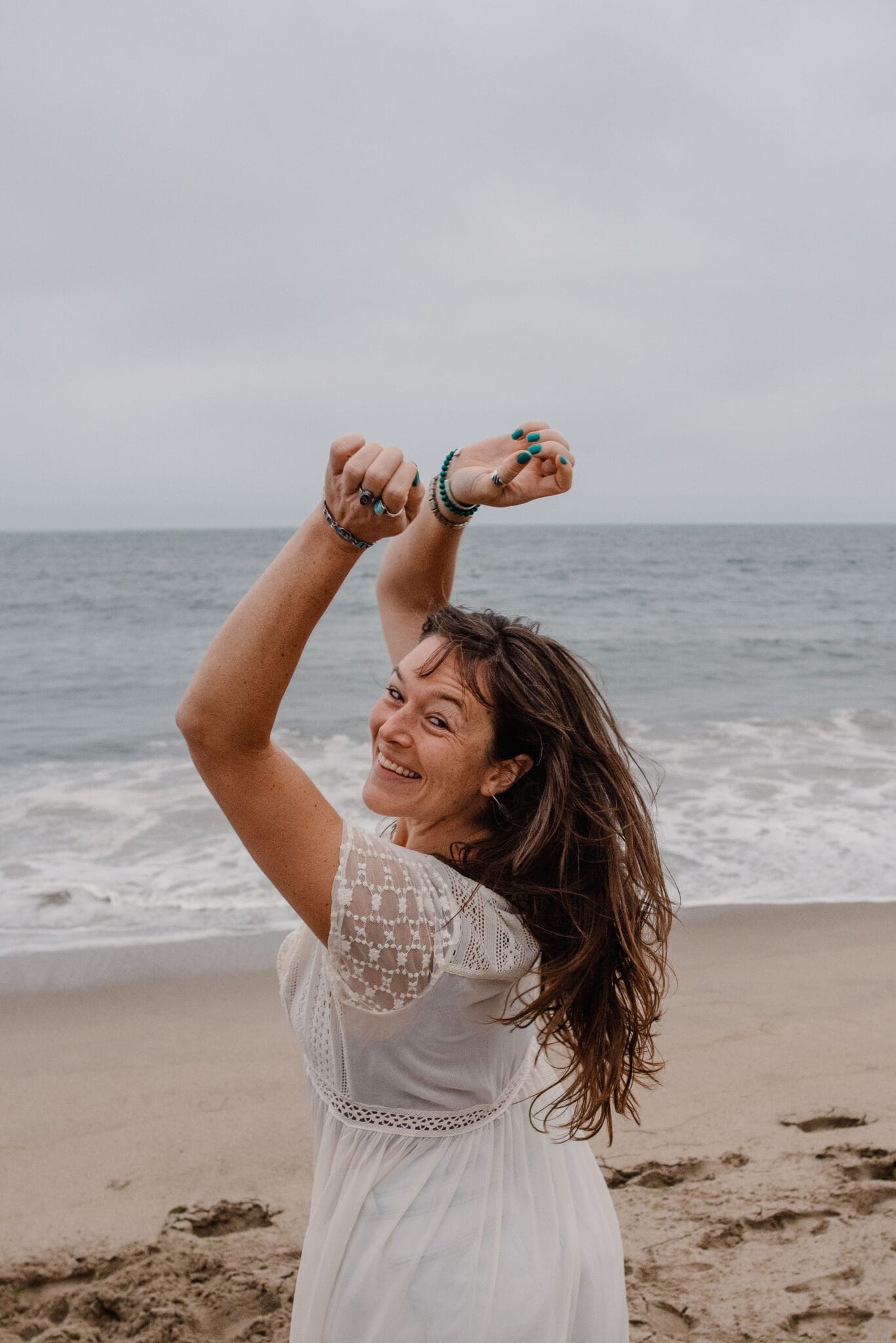 woman feeling her desiers on a beach with arms up after learning how to reconnect with yoruself when you feel lost