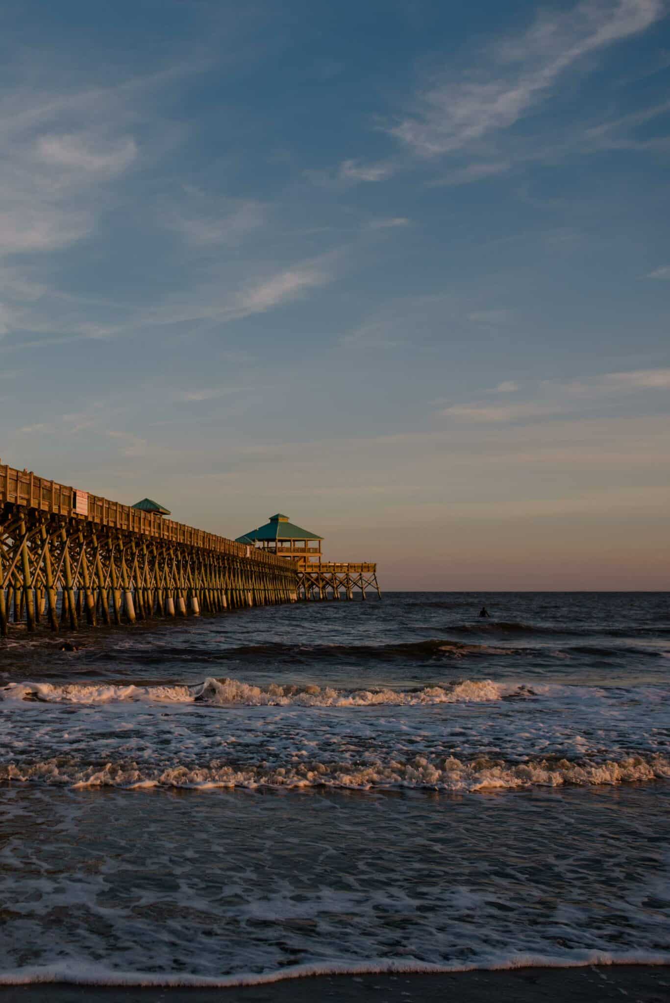 sunrise on an ocean with a dock in the distance