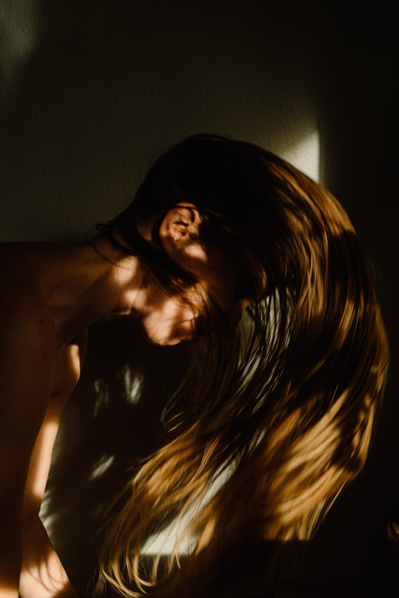 woman in the shadows with her hair spinning around her wondering how to feel her feelings and feeling feels