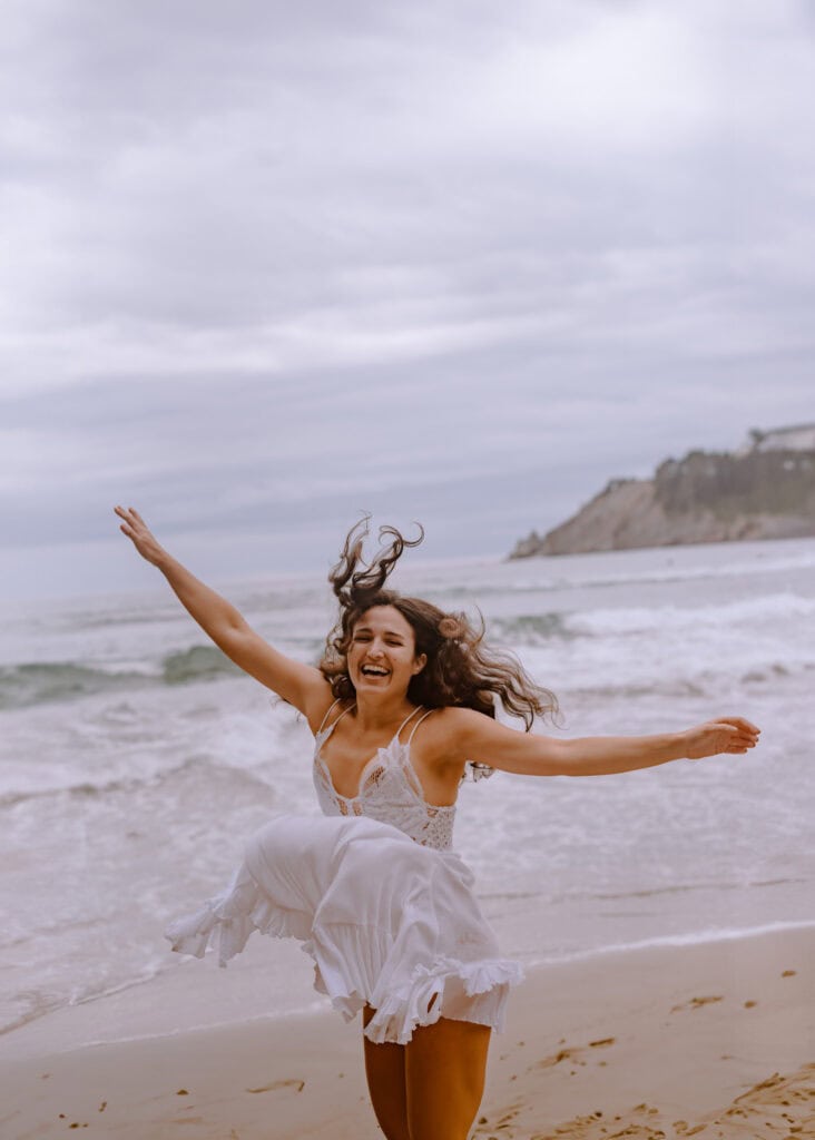 woman dancing on coast during boudoir photography in oregon