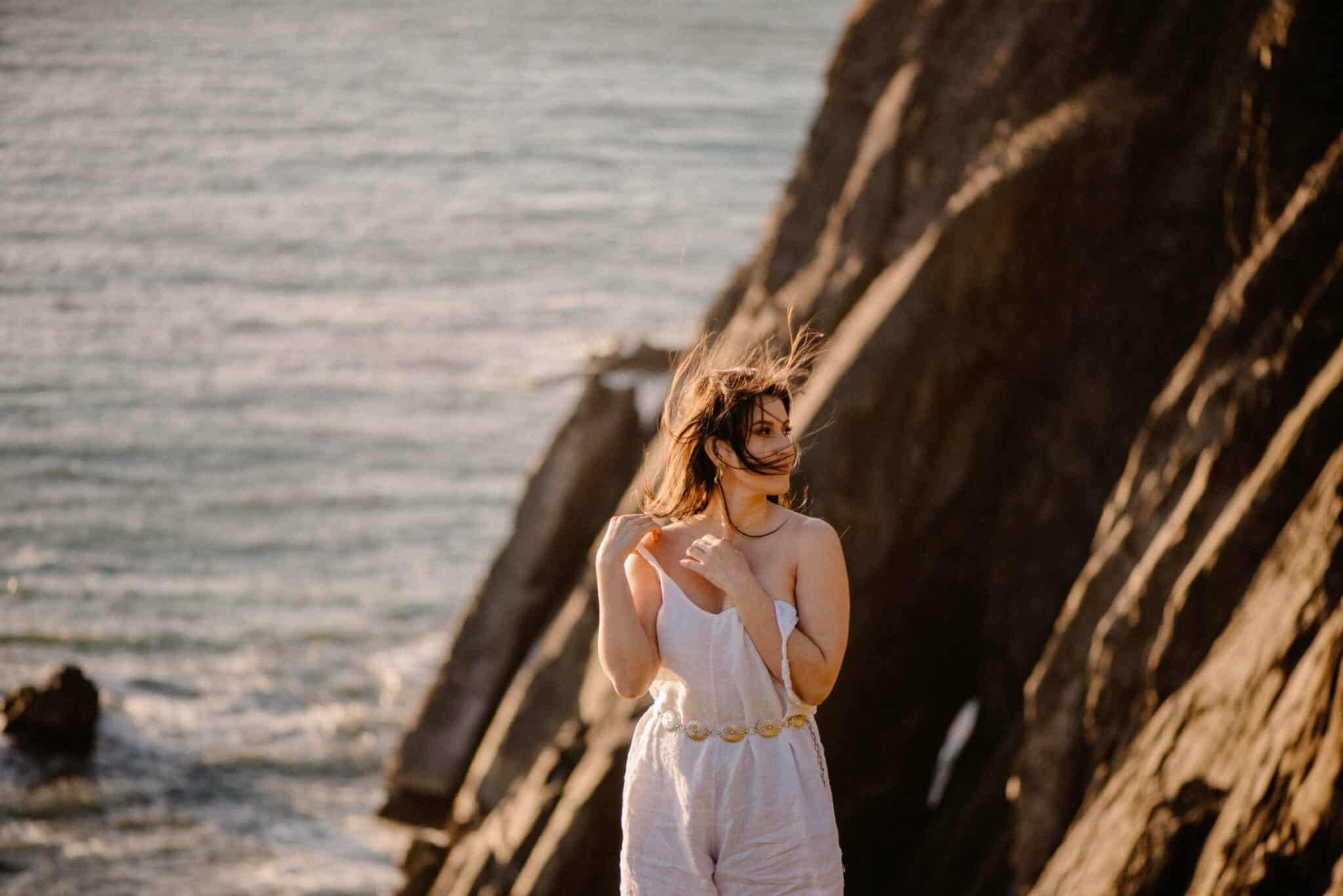 woman on cliff edge looking to side during during self-love boudoir photo shoot