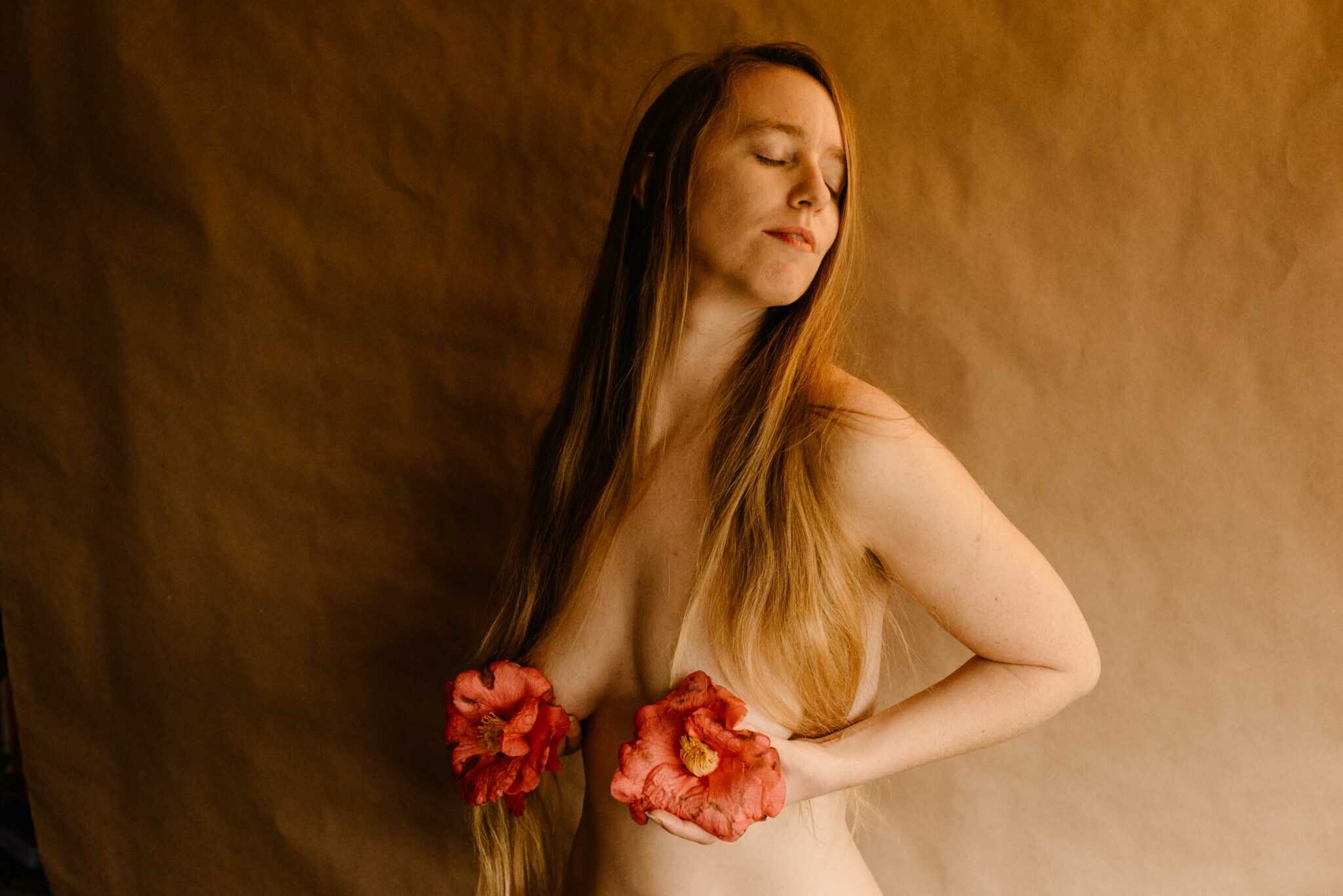 woman holding a camellia in her hands covering her chest