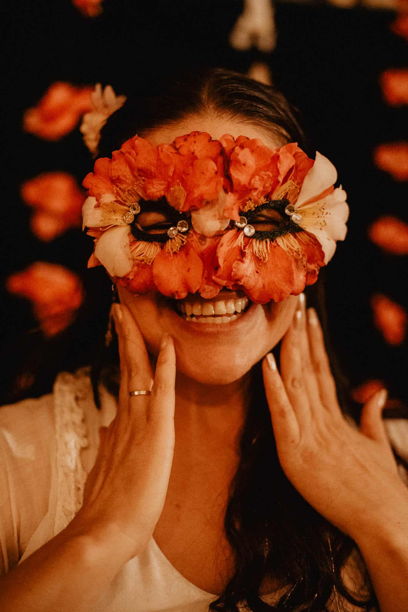woman holding her cheeks wearing a mask made of Camellia's smiling while she shows the camellia flower symbolism meaning and spiritual meanings