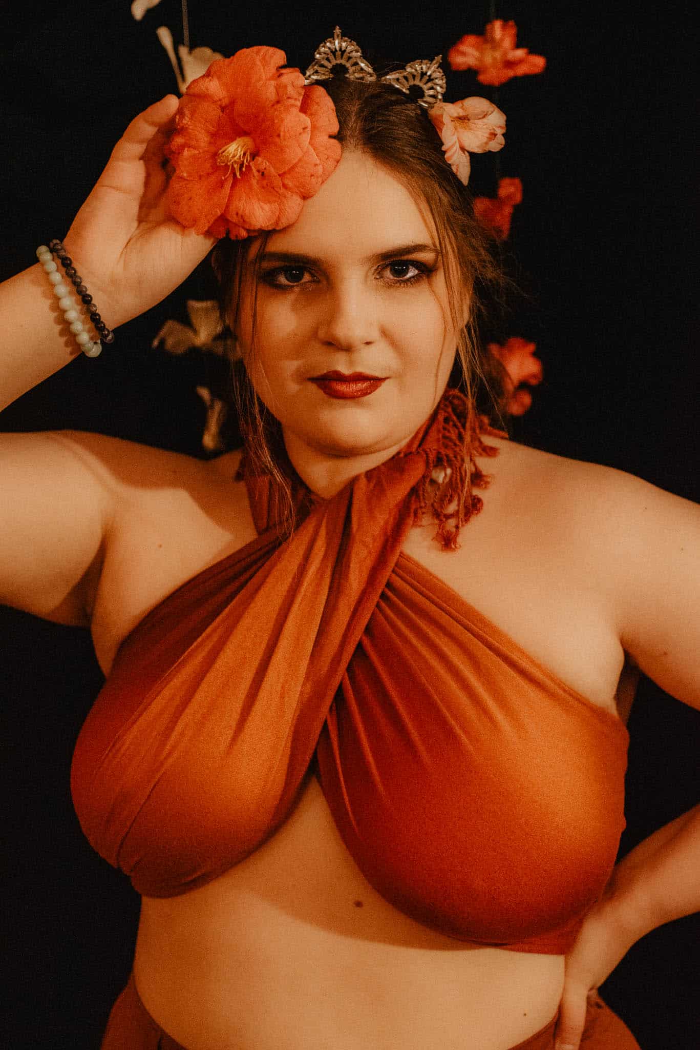 woman holding a camellia up to her forhead wearign a flower crown showing the camellia flower symbolism meaning and spiritual meanings