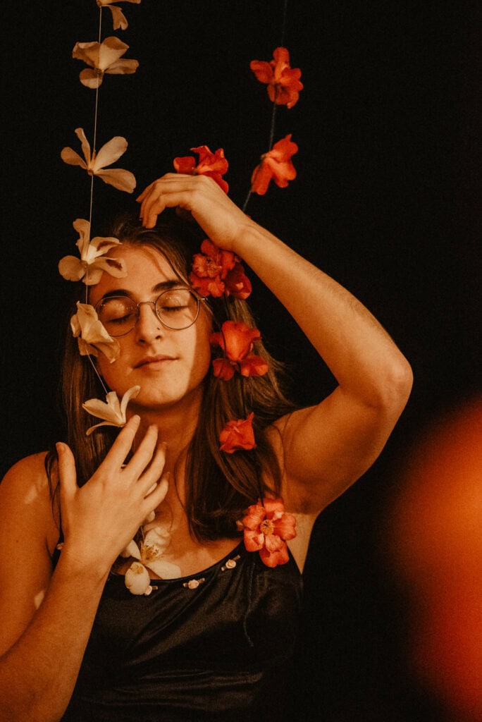 woman playing with Camellia flowers shows the camellia flower symbolism meaning and spiritual meanings