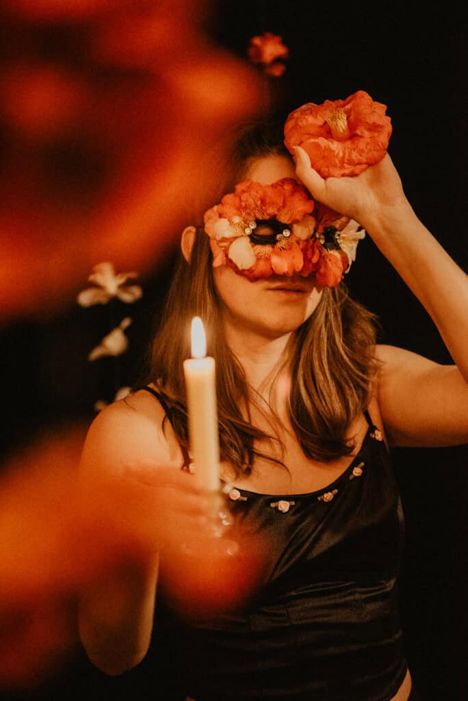 Camellia flower symbolism meaning with a woman holding a candle holding up the camellia