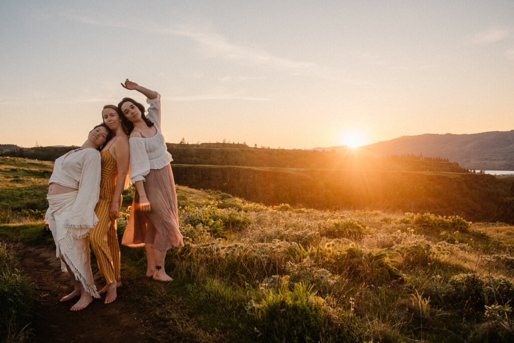 women gathered around at sunset on a cliff outside leaning against each other in ceremony of celebrating the women they've been retreat and ceremony