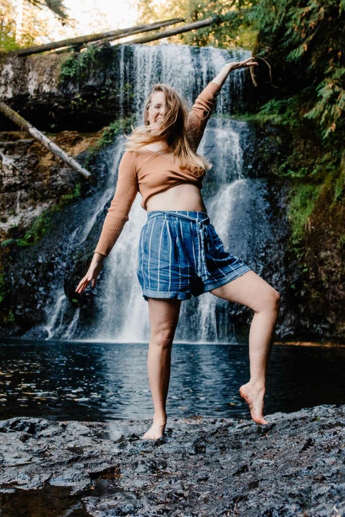 Lumalia lifting arms up near waterfall