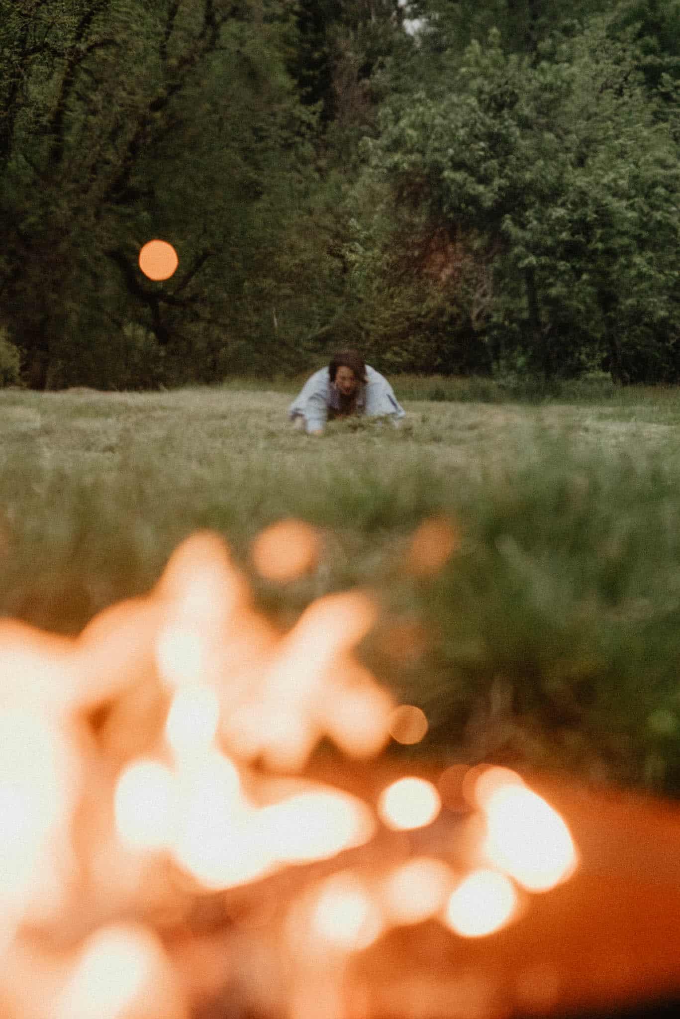 woman laying in ground releasing rage during a rage retreat using the power of the camas flower meaning during an emotional release ceremony with a fire in the forground