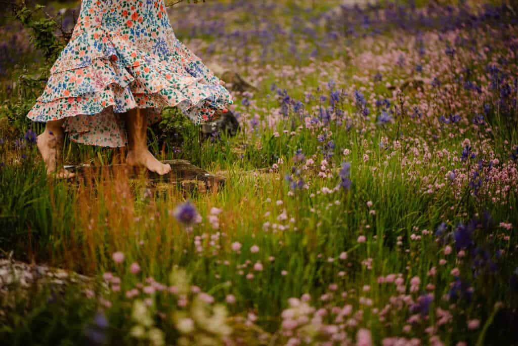 woman on a plath near wild flowers blooming her skirt flowing