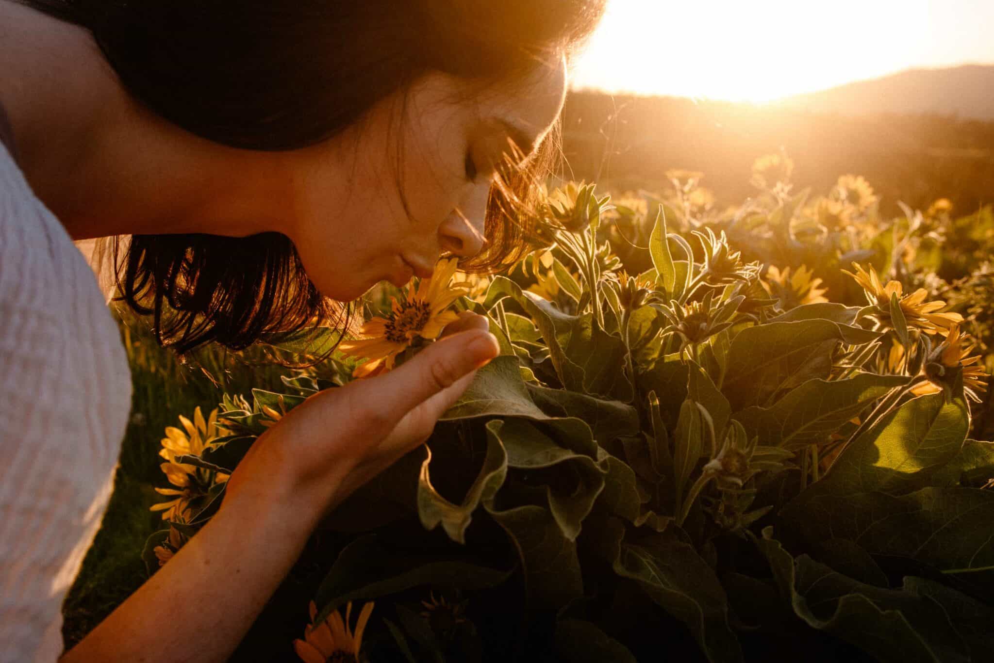 woman kissing a flower as the sunsets behind her