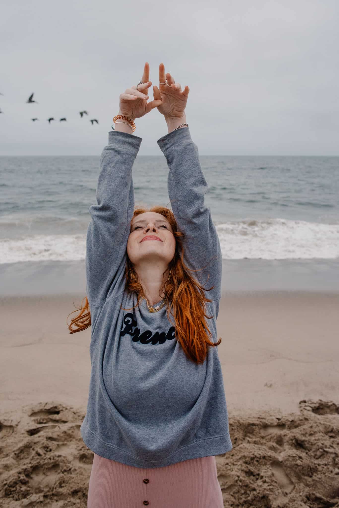 woman with her arms raised up near the ocean