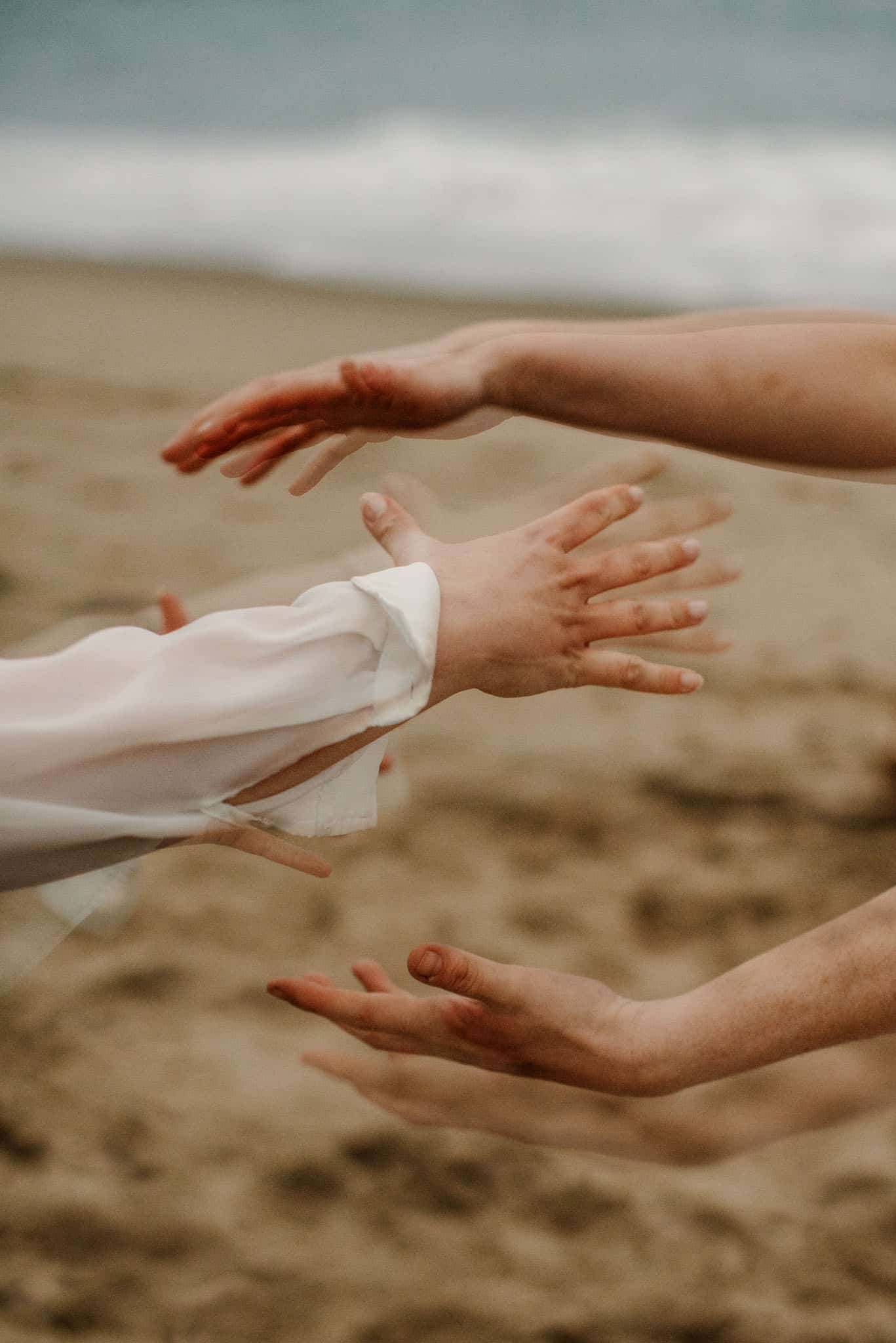 hands double exposed in a motion together near the ocean