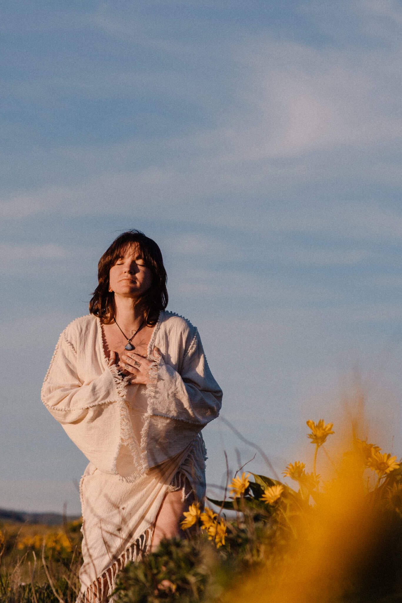 woman holding her heart near wild flowers
