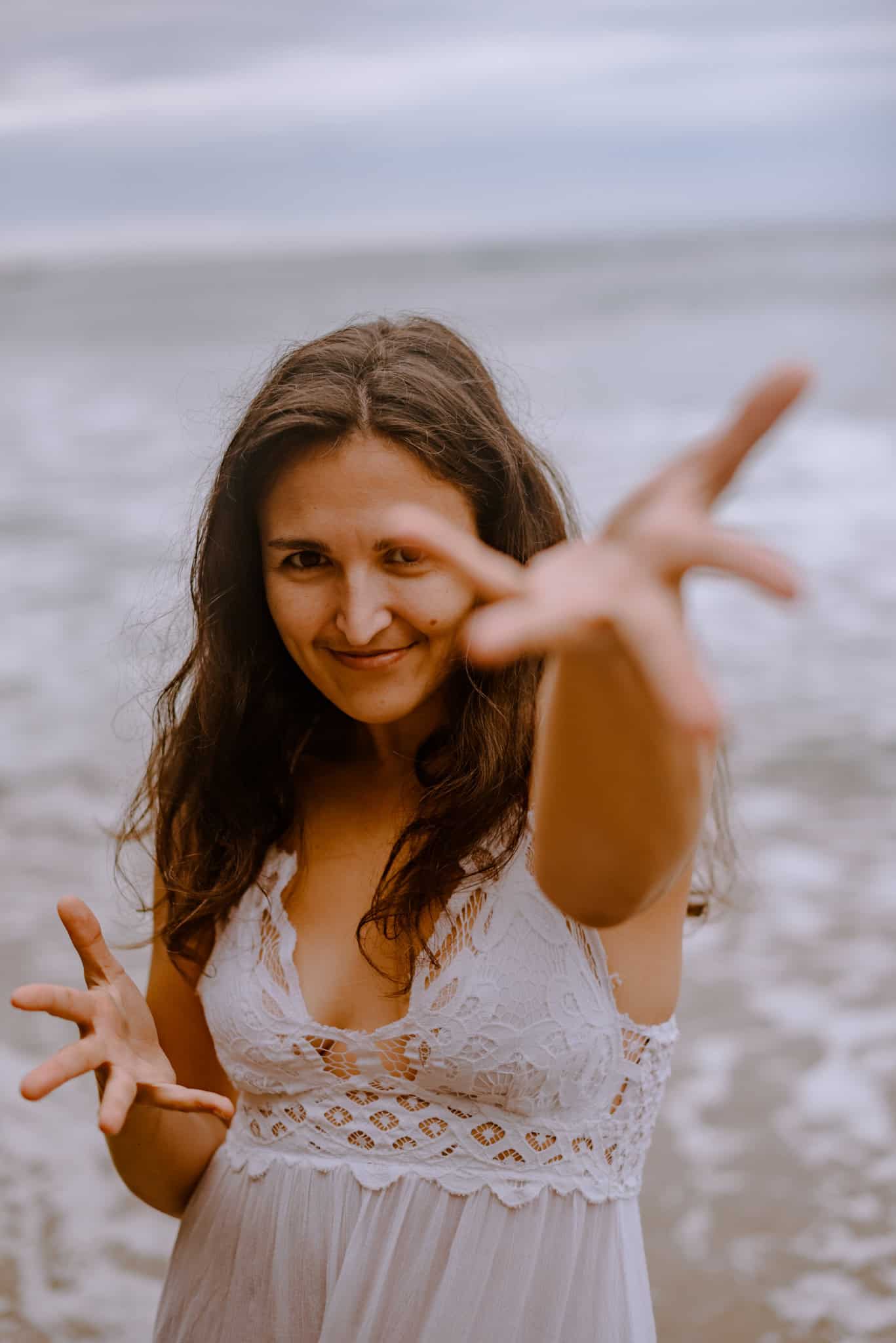 woman holding reaching hands out during immersive art somatic experience near a beach