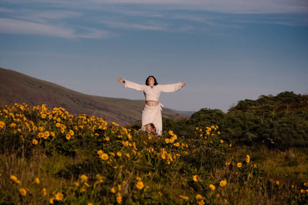 embodied experiences woman with arms out wide near flowers during a celebrate again experienced photographed by Lumalia