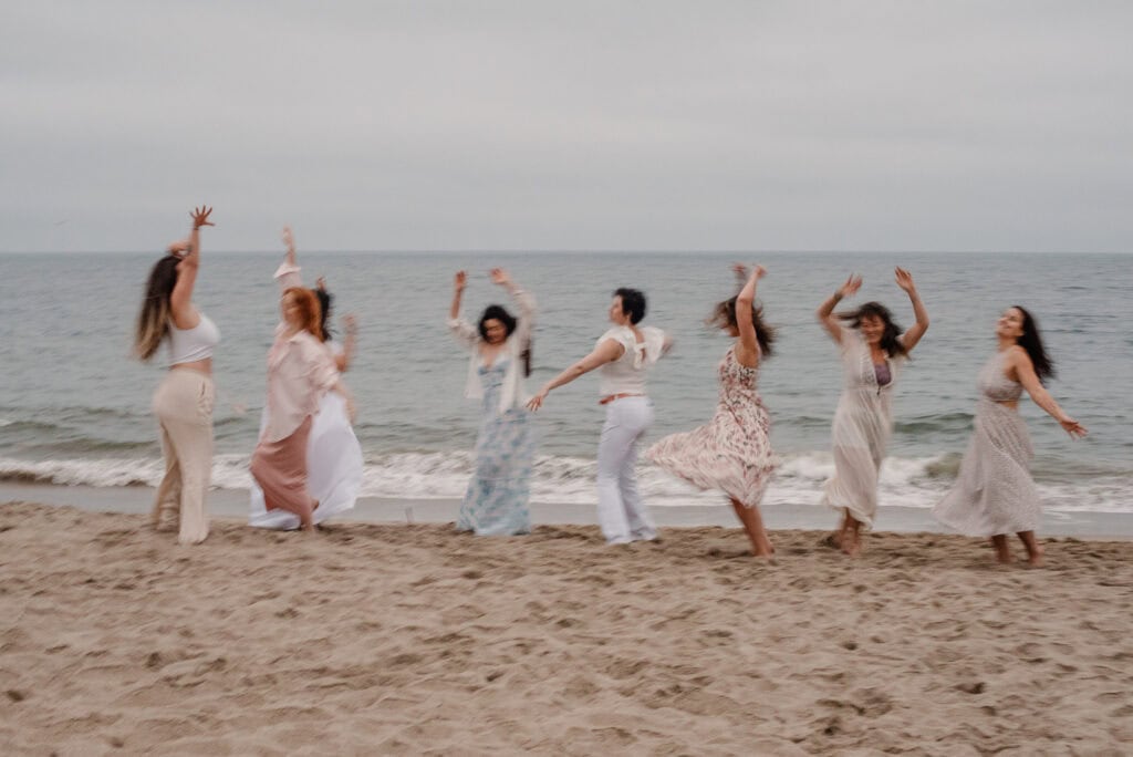 embodied experiences with women dancing around a coast with a celebrate again experience photographed by Lumalia