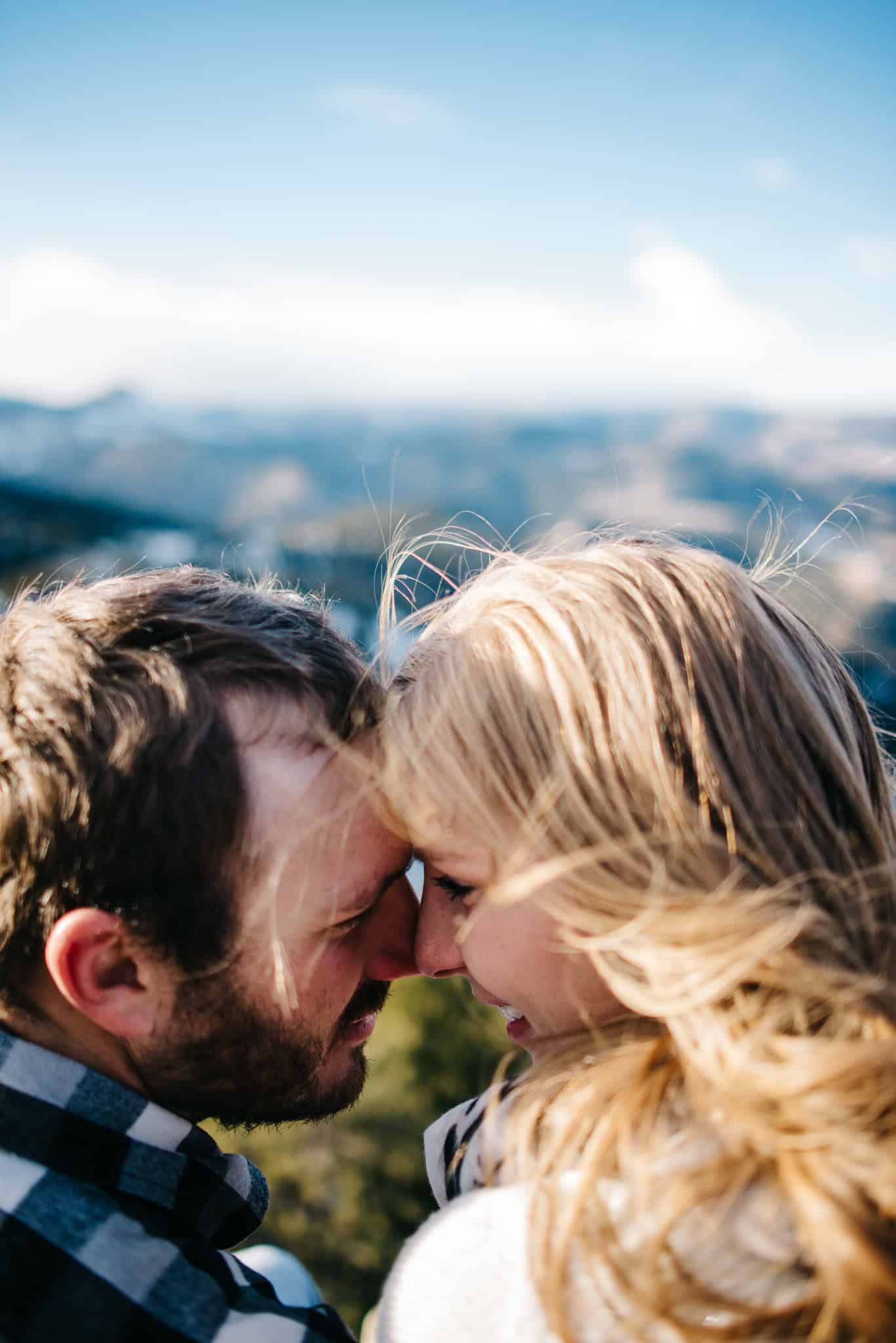 couple cuddling near mountain top during anniversary photography session with Lumalia