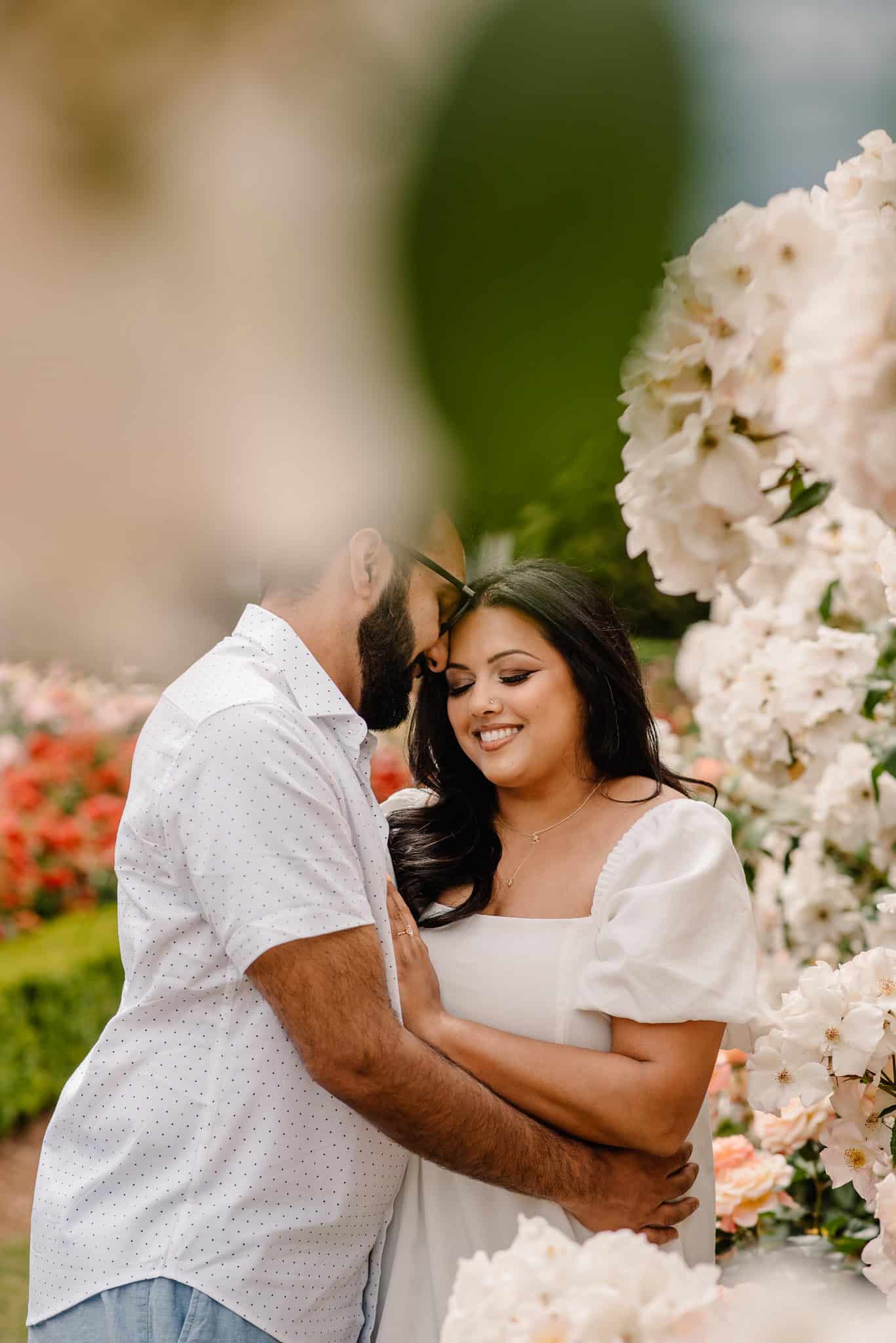 couple in a rose garden snuggling smiling during Portland couples anniversary photography experience