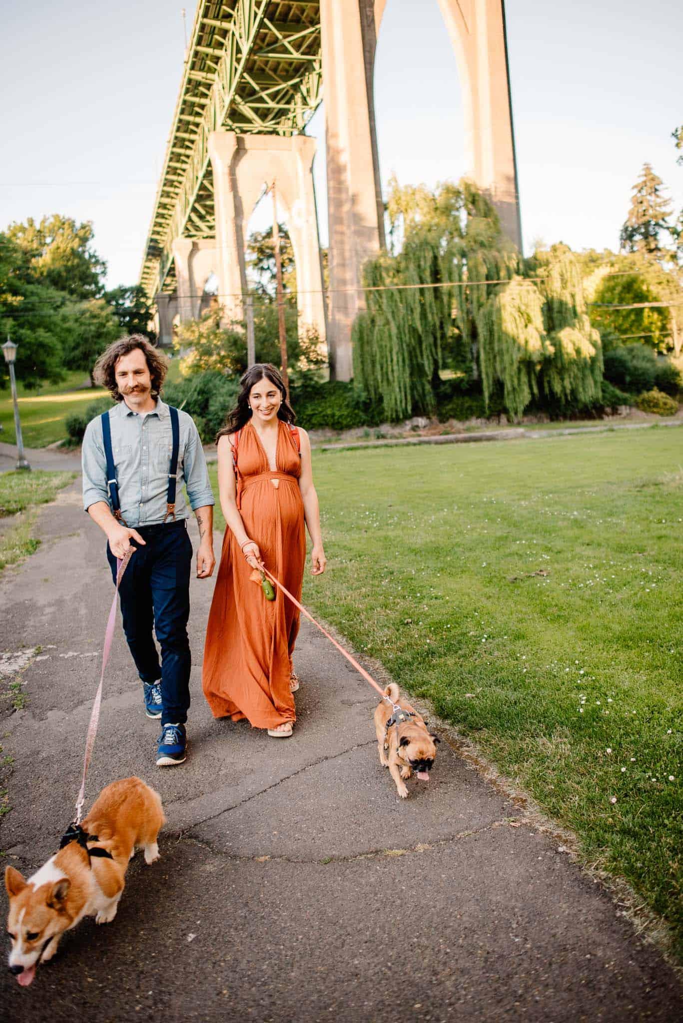 couple walking dogs during the Cathedral Park St John's Bridge during engagement photos in Cathedral Park