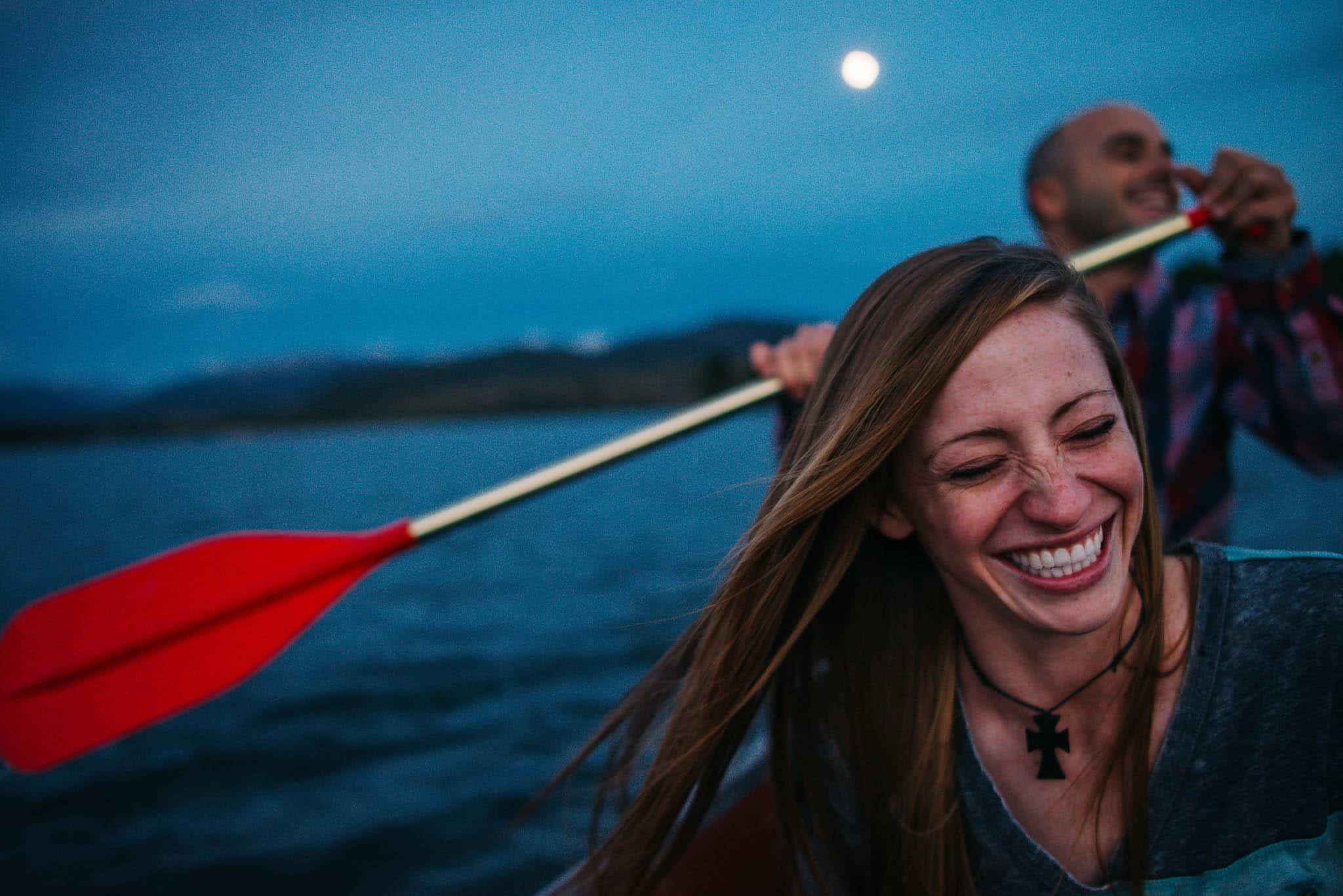 couple laughing in a boat near Cathedral park during engagement photos in Cathedral Park