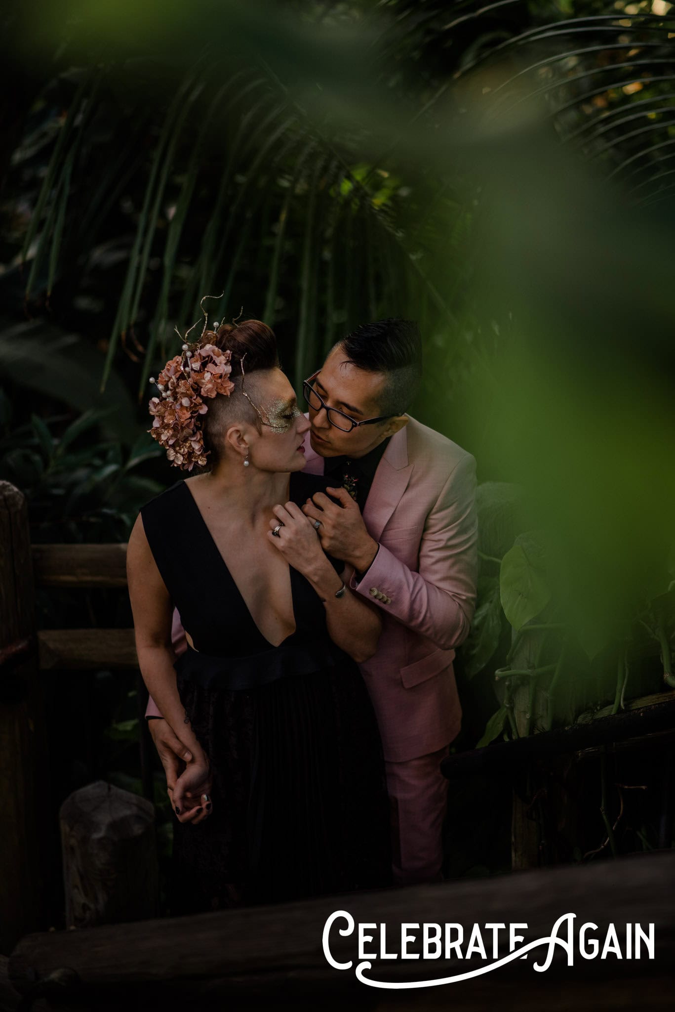 couple snuggling framed by a plant inside a green house at a engagement photo location in Portland, Oregon with Celebrate Again