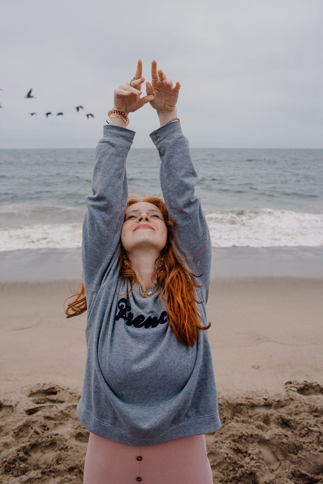 woman with her hands up near a coast in an aliveness experiences