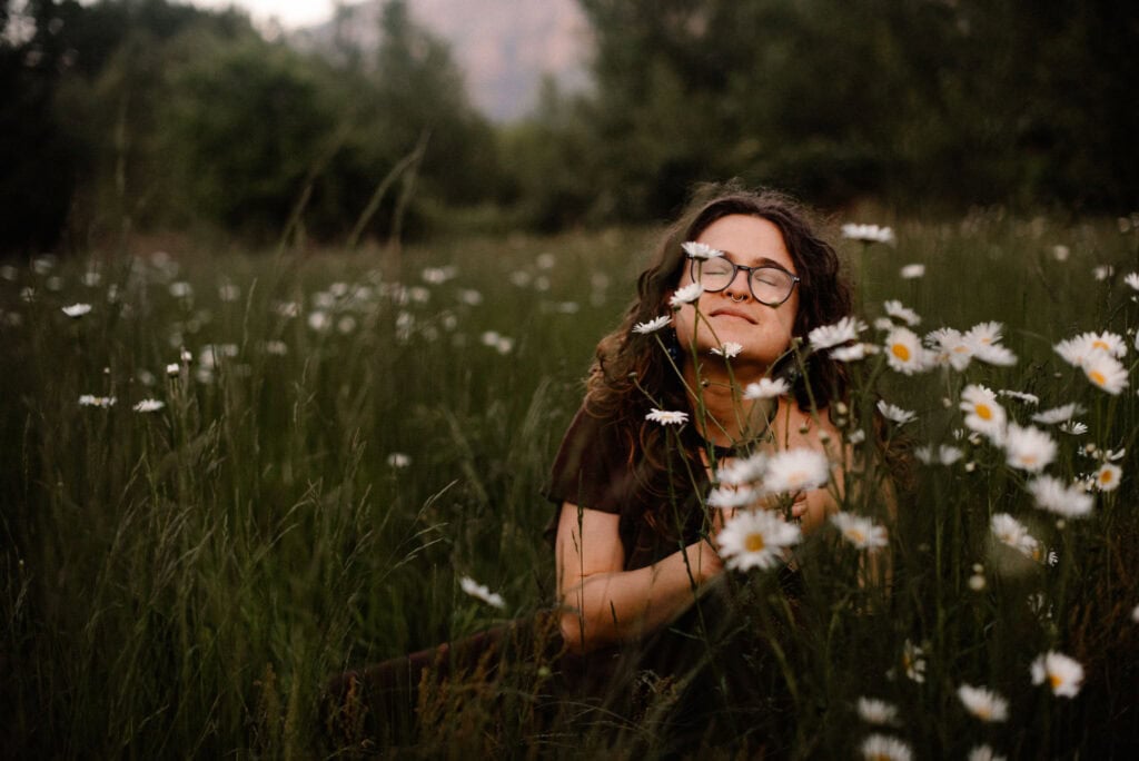 woman smiling in a daisy field in an aliveness experience