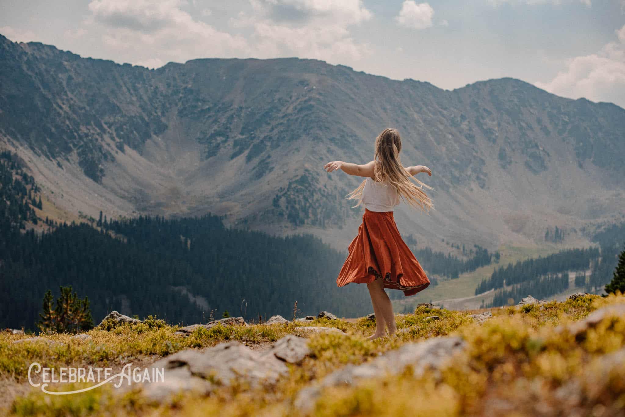 woman in mountian spinning on how to feel alive without blowing up your life in red dress
