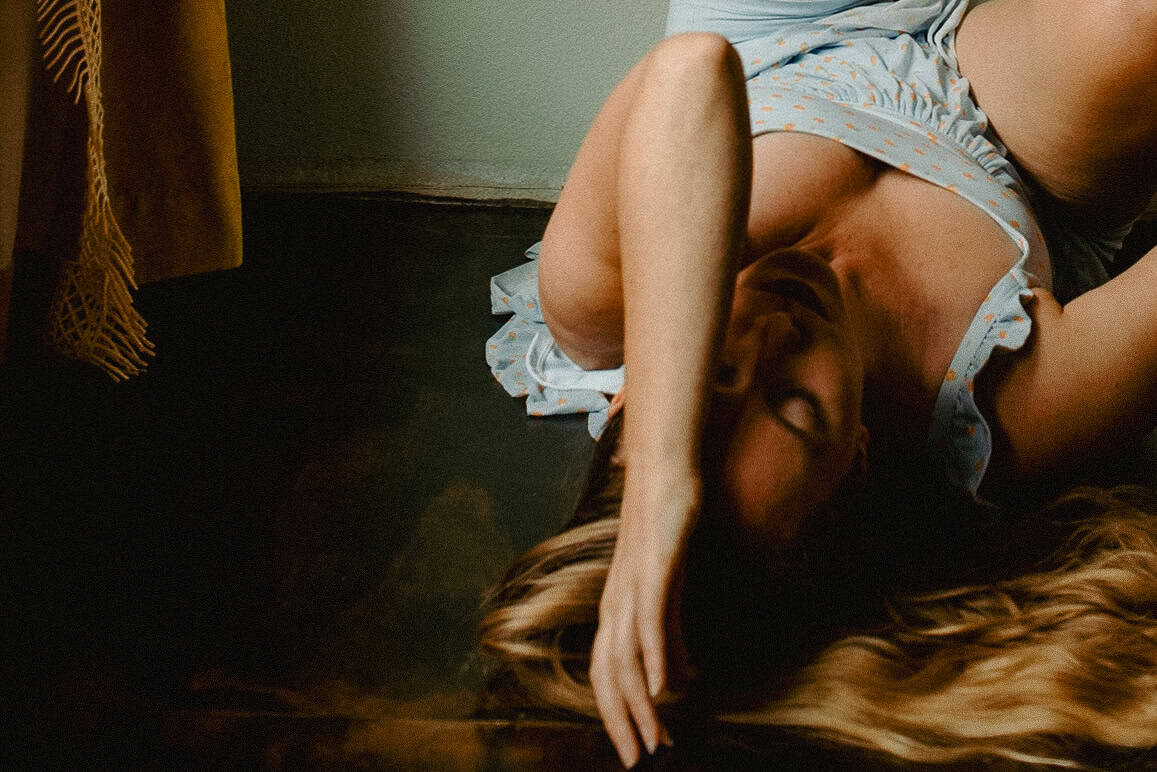 Lumalia moving through feelings of being in the messy middle of life on the floor in a self portrait